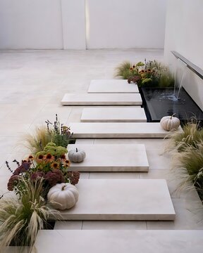 Modern stone stepping stones in a minimalist garden with decorative pumpkins and a water feature