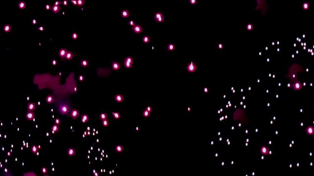 Vibrant crimson and white fireworks explode against the inky black evening sky, painting the darkness with bursts of light and dazzling spectacle.
