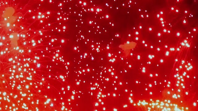Dazzling fireworks explode over City Park during the Summer Celebration, painting the night with radiant hues of red, gold, and pink during a lively, joyous display.