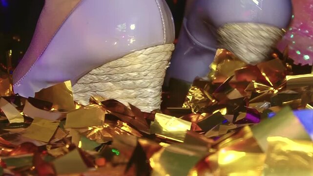 Shiny lavender wedges tread across radiant ground covered in shimmering gold confetti during lively midnight celebration where joy and luxury dance together under dim lights of exclusive party venue
