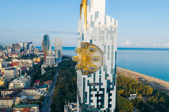 Aerial view of the iconic Alphabet Tower with its integrated ferris wheel structure, overlooking the modern skyline and the Black Sea coastline in Batumi, Adjara, Georgia.