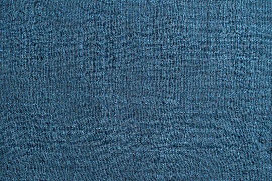 Closeup full frame background texture of rough woven blue linen fabric material. Natural rustic textile canvas pattern or coarse organic cloth backdrop