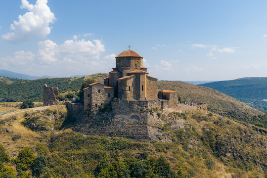 Aerial view of Jvari Monastery, an ancient stone church perched on a hilltop overlooking the surrounding landscape with rolling hills and a clear blue sky in Mtskheta, Mtskheta-Mtianeti, Georgia.