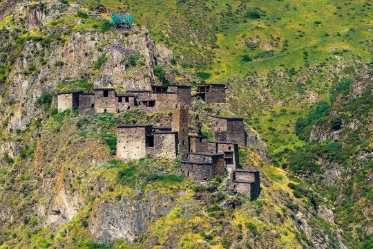 Aerial view of the historic medieval village of Mutso, featuring ancient stone towers perched on a steep rocky cliffside in the Caucasus Mountains, Mutso, Mtskheta-Mtianeti, Georgia.