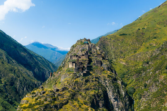 Aerial view of the historic medieval village of Mutso with its ancient stone towers perched on a rocky mountain ridge surrounded by lush green slopes in Mutso, Mtskheta-Mtianeti, Georgia.