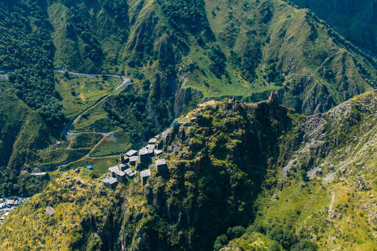 Aerial view of the medieval village of Mutso perched on a rocky mountain ridge with stone towers and houses surrounded by lush green slopes in Mutso, Mtskheta-Mtianeti, Georgia.