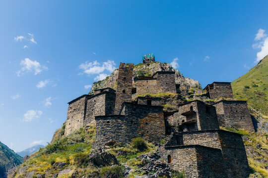 Aerial view of the historic medieval village of Mutso with its ancient stone towers perched on a rocky mountain slope under a clear blue sky in Mutso, Mtskheta-Mtianeti, Georgia.
