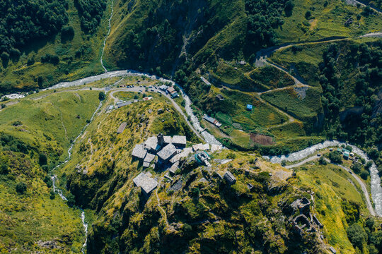 Aerial view of Mutso, a historic medieval village with stone towers and houses perched on a rocky mountain ridge above a winding river valley, Mutso, Mtskheta-Mtianeti, Georgia.
