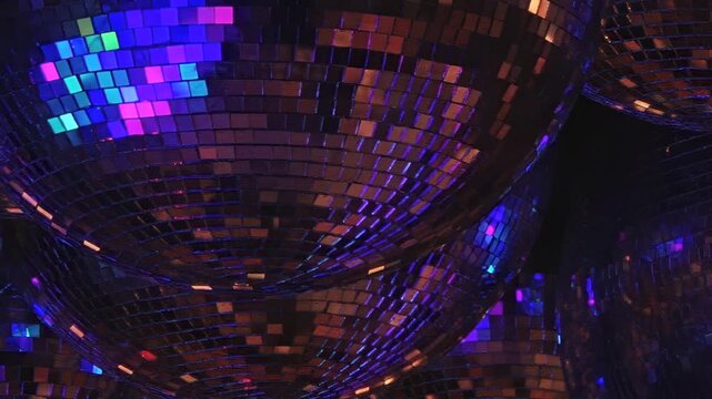 Numerous shimmering disco balls fill air, their myriad facets catching and casting dazzling array of shifting blue, green, and purple lights, creating immersive, celebratory nighttime ambiance.