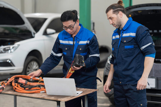 Electric vehicle car auto services. EV Wire Harness, High Voltage Cable, Portable Charger. Electrician checks or diagnostic wire harnesses for electric vehicle or EV car in auto workshop