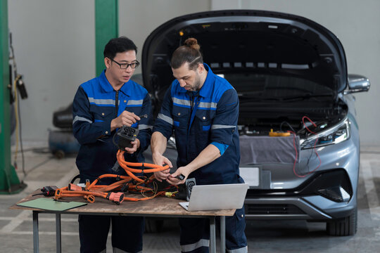 Electric vehicle car auto services. EV Wire Harness, High Voltage Cable, Portable Charger. Electrician checks or diagnostic wire harnesses for electric vehicle or EV car in auto workshop