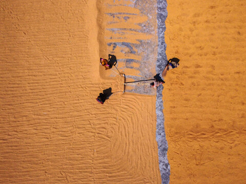 Aerial view of workers spreading harvested rice to dry on a large surface in Dhaka, Bangladesh.