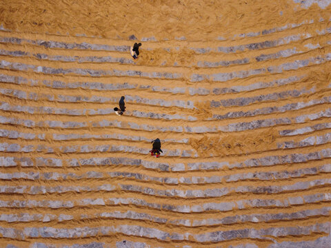 Aerial view of people working on rows of drying rice in a field in Dhaka, Bangladesh.