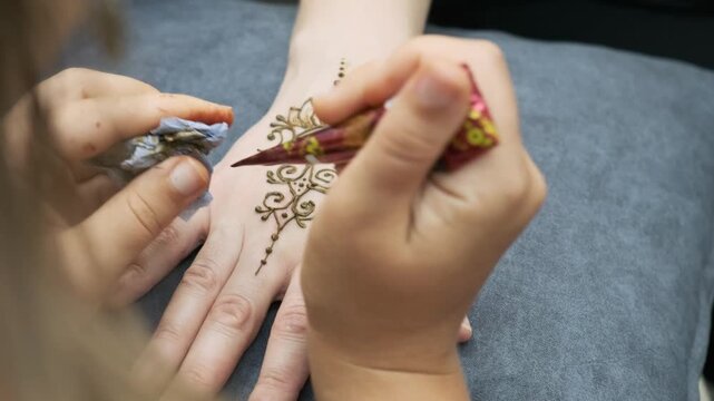 artist applying mehndi design on female hand with henna cone. traditional mehndi art creates beautiful temporary body tattoo. mehndi ceremony is popular cultural tradition for wedding
