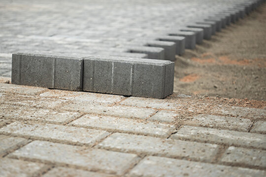 Paving stones laid out in a pattern during construction in a city park under cloudy skies