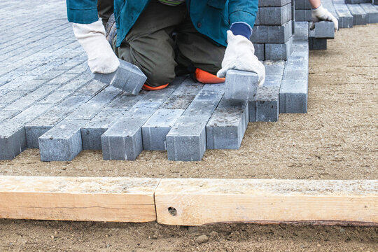 Workers laying bricks on a construction site in a residential area during the day