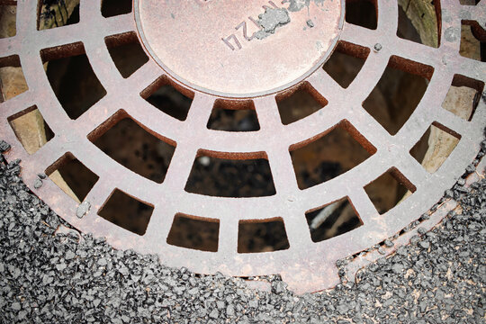 Rusty drain cover resting on asphalt during daylight in an urban environment