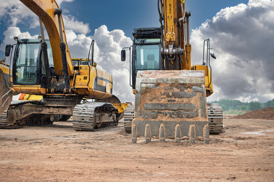 Heavy machinery working on construction site with cloudy sky in background during daytime