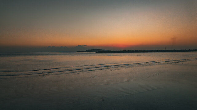 Aerial view of Gili Trawangan at sunset featuring calm waters and distant mountains Pemenang, West Nusa Tenggara, Indonesia.
