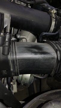 A black plastic air intake duct section located inside a car engine bay.