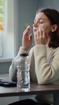Vertical video: Typing woman in sweater feeling eye strain, pausing, rubbing eyes at desk with keys