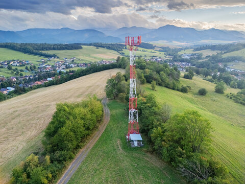 Aerial view of a red and white communication tower on a grassy hill with a dirt path, near the village of Jakubovany and the Western Tatras, Jakubovany, Zilina Region, Slovakia.