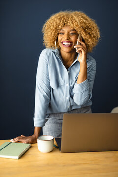 Smiling Woman Talking on the Phone at Her Desk in an Office