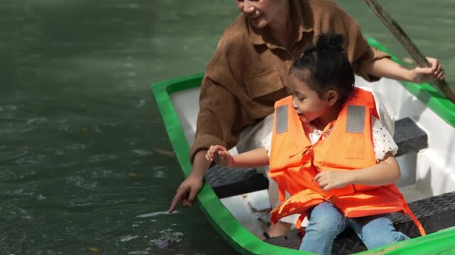 preschool child girl looking at fish in the water while boating with her mother

