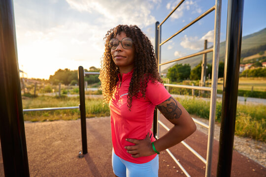 Woman posing at outdoor gym after workout at sunset