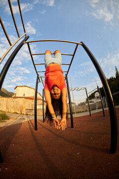 Happy girl smiling upside down on monkey bars
