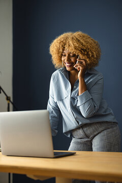 Woman Talking on Phone While Working at a Desk With a Laptop
