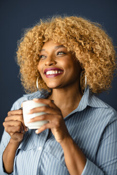 Woman Holds Cup and Smiles in Indoor Setting