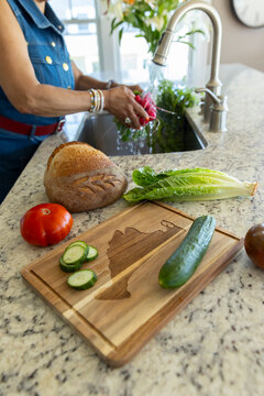 Senior Black black woman prepare salad  cutting board 