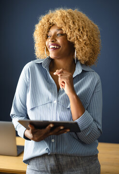 Smiling Woman Holding Tablet While Standing in Office
