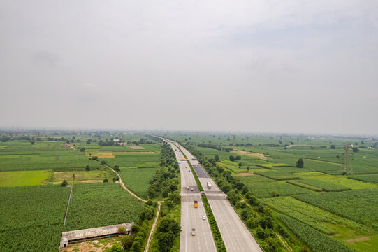 Aerial view of the Eastern Peripheral Expressway cutting through lush green agricultural fields in the rural landscape of Sonipat, Haryana, India.
