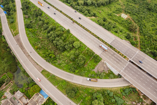 Aerial view of the Eastern Peripheral Expressway with vehicles driving on the multi-lane highway surrounded by lush green vegetation and trees in Sonipat, Haryana, India.