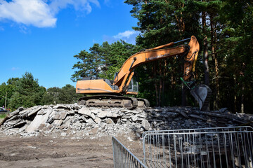 Heavy tracked excavator standing on pile of crushed concrete debris © Olesia