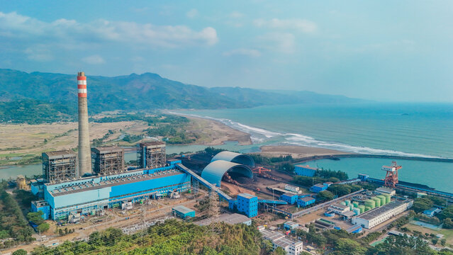 Aerial view of industrial landscape showing power plant and green surroundings symbolizing the challenge between energy demand and environmental protection.