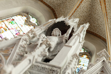 Fototapeta premium A religious ceremony takes place in a catholic church. Angel statue of a saint stands near the altar as worshippers gather for the mass.