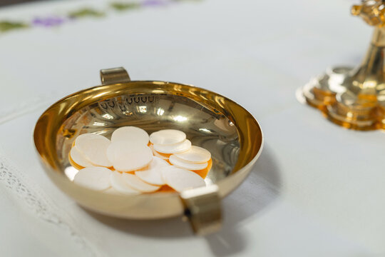 During a holy mass, communion hosts rest in a gold dish on the altar of the catholic church. The ceremony follows the rituals of the faith.