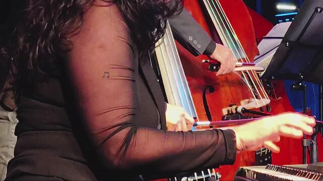 Woman pianist playing during a live tango concert in a theater, with a doble bass at background