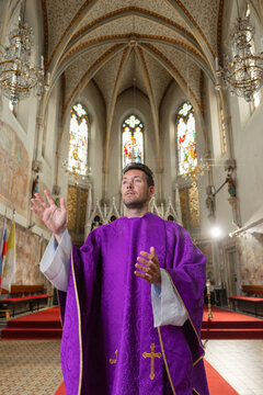 A priest stands in a church in Europe, conducting a holy mass and engaging with the congregation during the service.