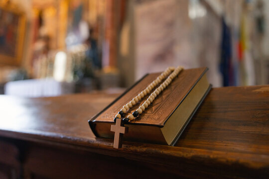 A religious ceremony is taking place in a catholic church. A bible and rosary are on the altar as part of the service.
