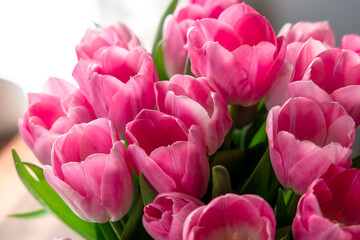 Obraz premium Bright tulips are arranged in a vase and placed near a window where light shines through in a cheerful setting
