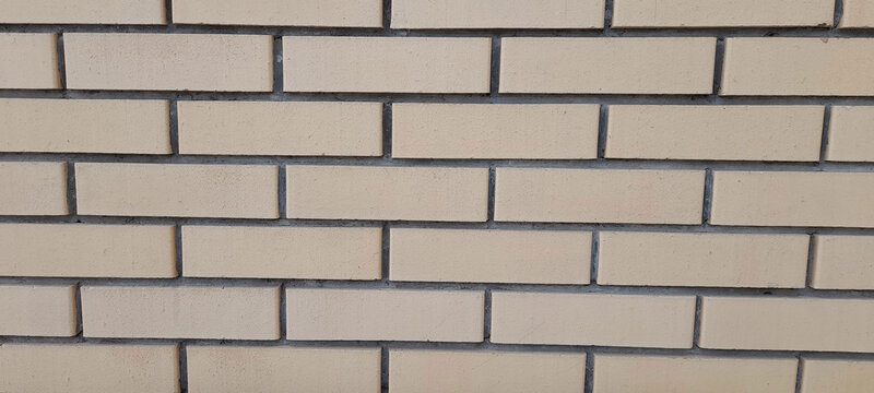Flat lay close-up of a modern light-colored brickwork masonry wall with symmetrical rectangular blocks. 