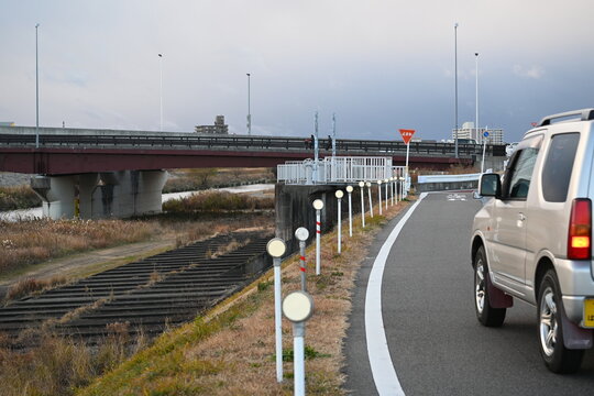 堤防道路を走る車と並ぶ視線誘導標