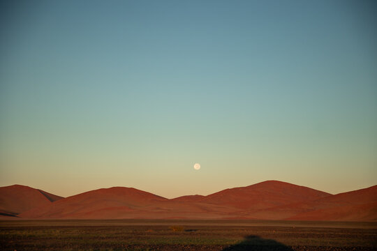 Full moon rising over red sand dunes in Namib-Naukluft Park