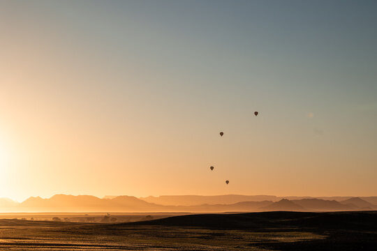 Hot air balloons flying over Namibian desert at sunrise