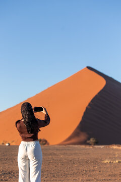 vertical Woman photographing Sossusvlei dune in Namib Desert, Namibia