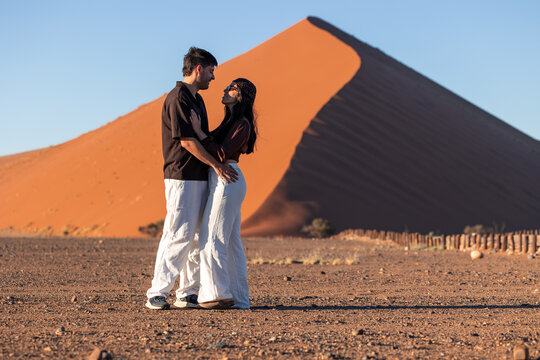 Couple embracing in Namib desert with red dune